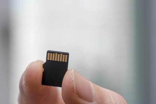 Young man is holding a tiny memory card in his hand, text space