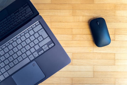 Cutout of a modern laptop keyboard and mouse on the wooden floor with text space