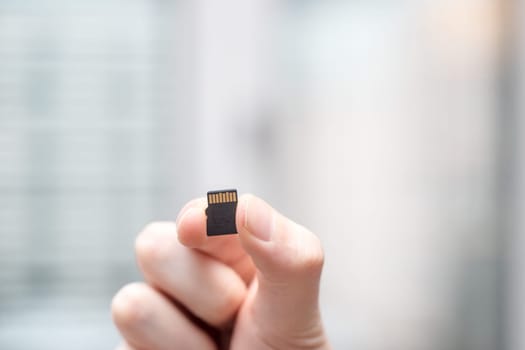 Young man is holding a tiny memory card in his hand, text space