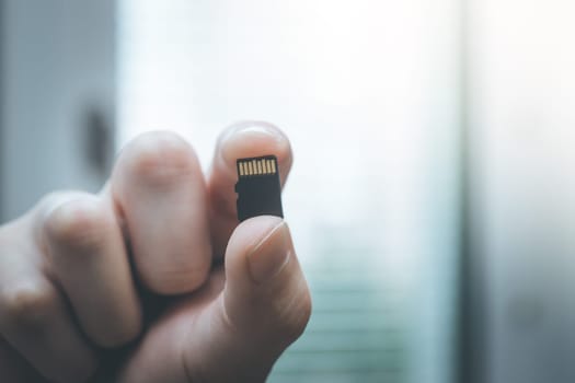 Young man is holding a tiny memory card in his hand, text space