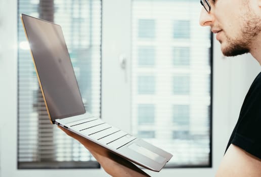 Young freelancer in black shirts holds up a very thin, elegant Ultrabook