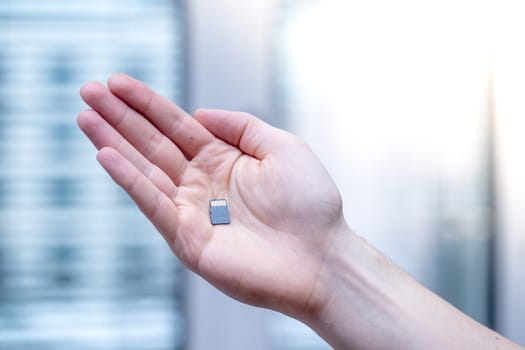 Young man is holding a tiny memory card in his hand, text space