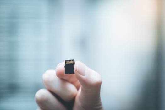 Young man is holding a tiny memory card in his hand, text space
