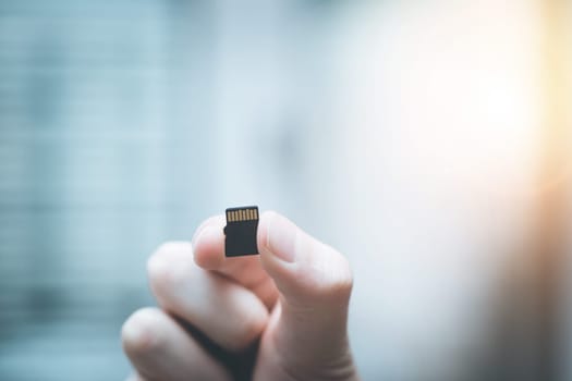 Young man is holding a tiny memory card in his hand, text space