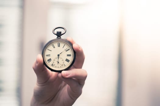 Time goes by: Man is holding a vintage watch in his hand, business context, copy space