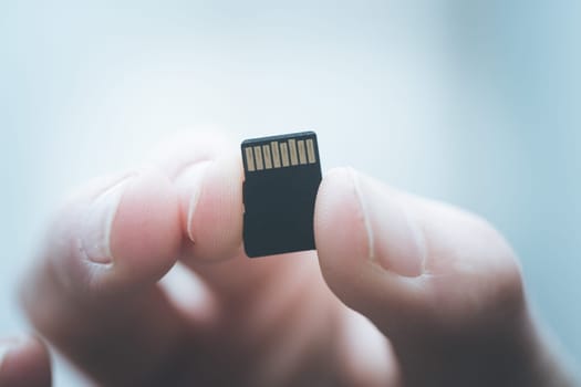 Young man is holding a tiny memory card in his hand, text space