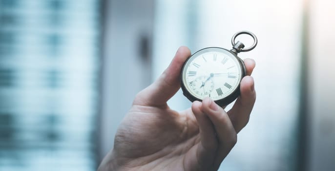Time goes by: Man is holding a vintage watch in his hand, business context, copy space