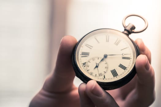 Time goes by: Man is holding a vintage watch in his hand, business context, copy space