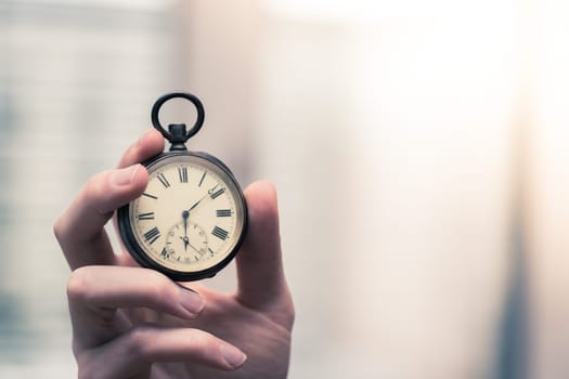 Time goes by: Man is holding a vintage watch in his hand, business context, copy space