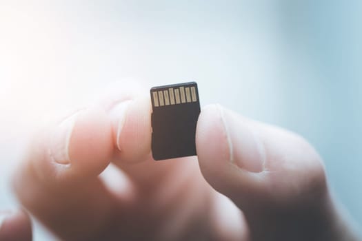 Young man is holding a tiny memory card in his hand, text space