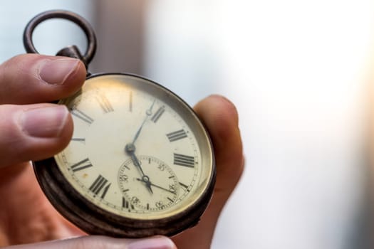 Time goes by: Man is holding a vintage watch in his hand, business context, copy space