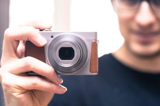 Young man with vintage camera smiles and takes a photo