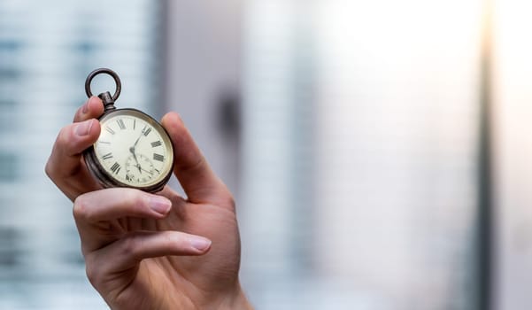 Time goes by: Man is holding a vintage watch in his hand, business context, copy space