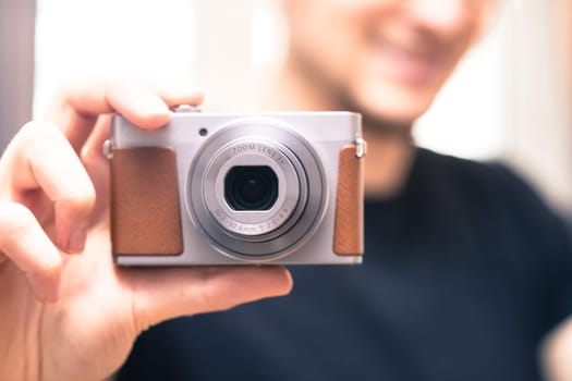 Young man with vintage camera smiles and takes a photo