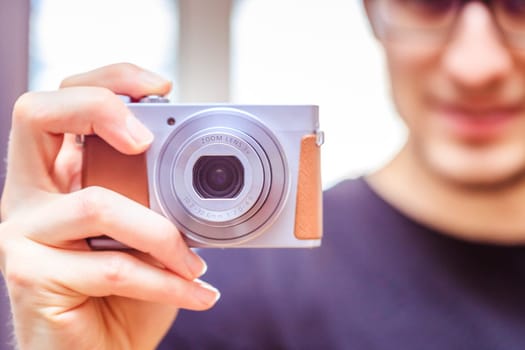 Young man with vintage camera smiles and takes a photo