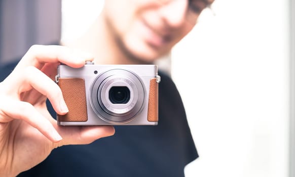 Young man with vintage camera smiles and takes a photo