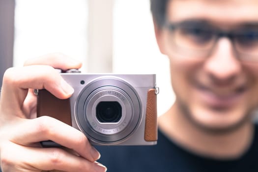 Young man with vintage camera smiles and takes a photo