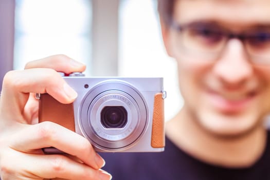 Young man with vintage camera smiles and takes a photo