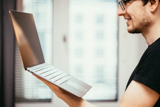 Young freelancer in black shirts holds up a very thin, elegant Ultrabook