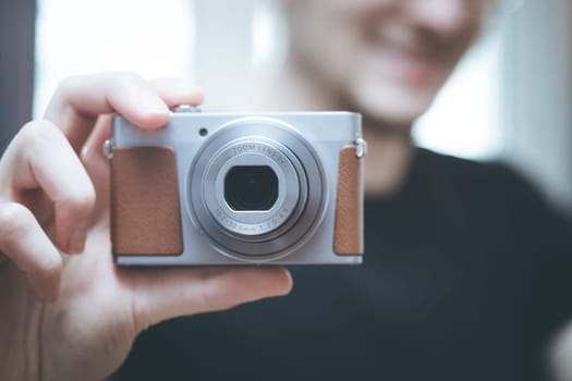Young man with vintage camera smiles and takes a photo