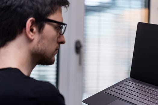 Young man holding a modern laptop in front of the window, business