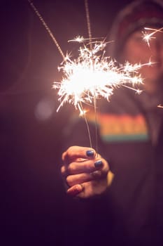 Smiling girl is holding a sparkler in her hand, new year, outdoors