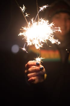 Smiling girl is holding a sparkler in her hand, new year, outdoors