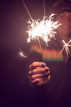 Smiling girl is holding a sparkler in her hand, new year, outdoors