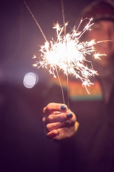 Smiling girl is holding a sparkler in her hand, new year, outdoors