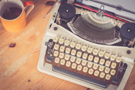 Vintage typewriter, glasses and cup of coffee on a wood desk