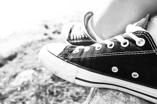 Black sneakers and green grass in the summer: free time for teenager