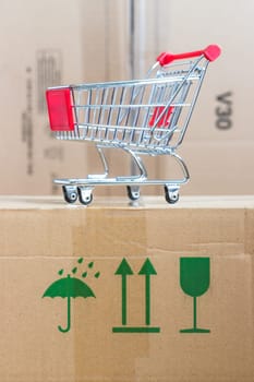 Online-Shopping and parcel service concept: Miniature shopping cart and cardboard boxes