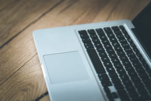 Close up of a laptop keyboard on a rustic wooden desk