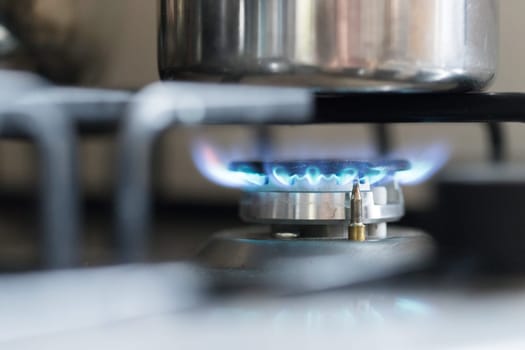 Close up of a blue gas flame, cooking a water pot in kitchen