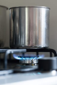 Close up of a blue gas flame, cooking a water pot in kitchen