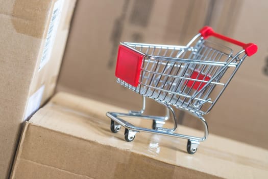 Online-Shopping and parcel service concept: Miniature shopping cart and cardboard boxes