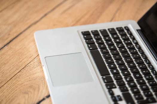 Close up of a laptop keyboard on a rustic wooden desk