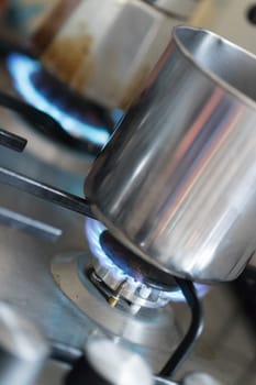 Close up of a blue gas flame, cooking a water pot in kitchen
