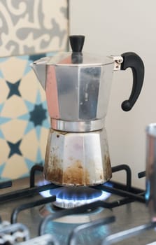 Close up of a blue gas flame, cooking a water pot in kitchen