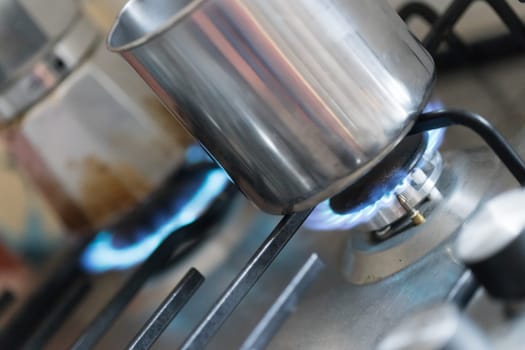 Close up of a blue gas flame, cooking a water pot in kitchen