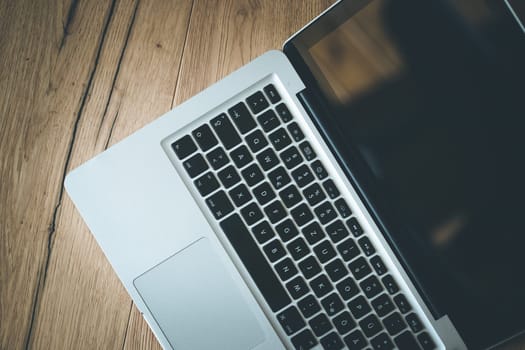Close up of a laptop keyboard on a rustic wooden desk