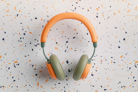 Orange and green vintage headphones on terrazzo background, 3D rendering