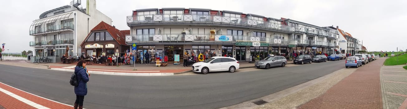 Bensersiel, Germany - May 12, 2021: Panorama view of the well-frequented row of shops in Bensersiel with overcast skies during the corona pandemic.