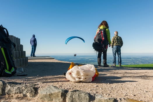 Close-up view of the take-off point for paragliders on the Tegelberg in Bavaria with planes that have just started and people looking behind with a blue sky in summer.