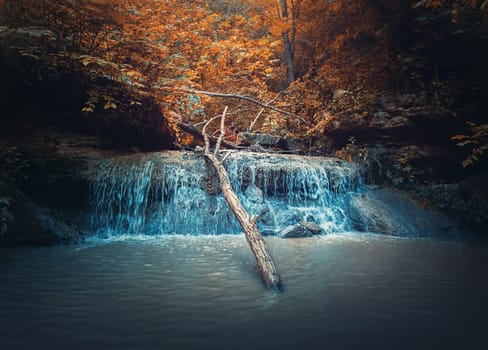Small creek waterfall with water falling through the autumn woods. Fast stream flowing down from the spring in the forest, through the hills. Saharna cascade called Gypsy Hole, Moldova