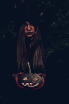 Portrait of woman ghost horror her have pumpkin on hand in forest, halloween day concept