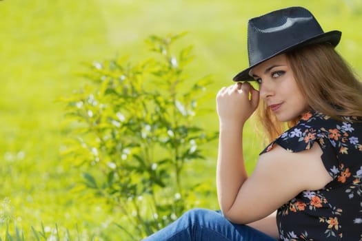 Portrait of beautiful young woman in black hat looking at the camera. Horizontally.