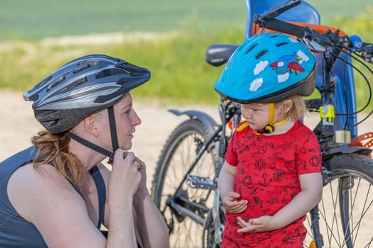 Cycling safety concept. Mother with her son using safety helmet. All potential trademarks are removed.