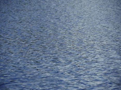 small ripples on the surface of the river abstract blue background