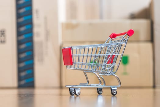Online-Shopping and parcel service concept: Miniature shopping cart and cardboard boxes